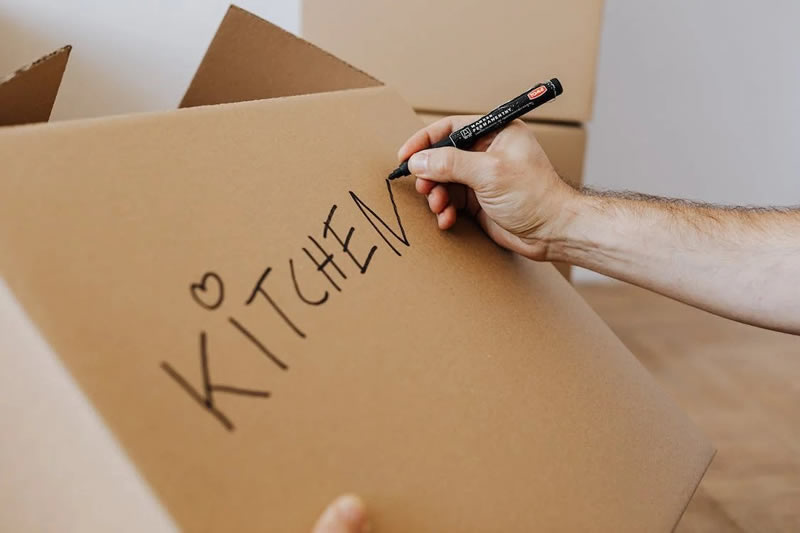 A man labeling a cardboard box.