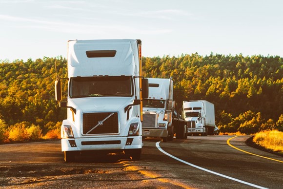 three white trucks on a road