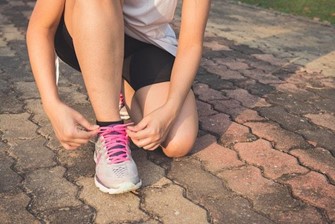 A woman lacing up her running shoes.